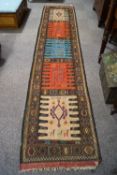 An Afghan runner with five alternating coloured square panels depicting stylised motifs,