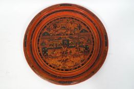 A Burmese lacquer tray, decorated in red, green and black, with figures in a garden,
