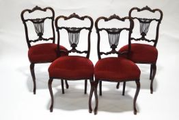 A set of four Victorian mahogany dining chairs with pierced backs and red upholstered seats on
