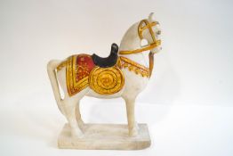 An Indian carved marble model of a horse standing proud, the saddle and bridle painted gold,