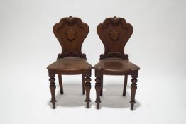A pair of Victorian oak hall chairs, the shaped backs with carved scroll detail,