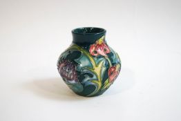 A Moorcroft vase, of bulbous form tube lined, with thistles and lilies on a green ground, 8.