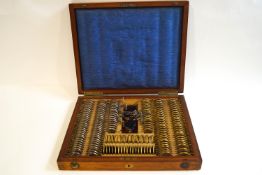 An Edwardian walnut case of optician's test lenses and equipment, the case stamped Salmon Brothers,