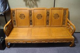 A Chinese hardwood three seat sofa with carved pierced back and solid seat,