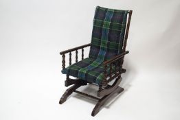 A Victorian American rocking chair with spindle sides and tartan upholstered seat and back
