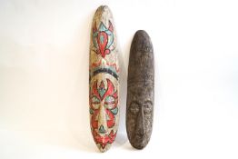 A tribal oblong wall mask with painted facial details, 62cm high, and a smaller similar example,