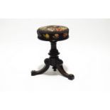 A Victorian piano stool with adjustable needlework seat on turned ebonised pedestal with three