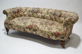 A Victorian sofa with low button back on turned legs with brass casters,
