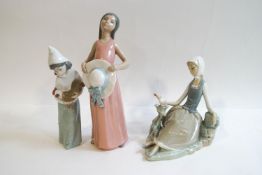 Three Lladro figures: Girl in a pink dress and bonnet, 26cm high, Seated girl with dove,