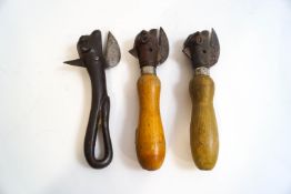 Three novelty can openers in the form of cow's heads, two with wooden handles,