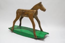 A rustic wooden rocking horse, on a painted base,