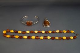 A modern amber torque bangle; an amber pendant;