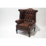 A 20th century leather wing button back armchair on cabriole legs,