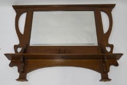 An Arts and Crafts oak framed over mantel mirror, with carved elliptical and heart decoration,