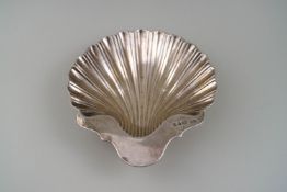 A Victorian silver shell shaped butter dish on three ball feet,