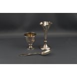 A silver egg cup and spoon, and quatrefoil spill vase on a loaded round base, 10.