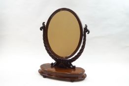 A Victorian mahogany oval dressing table mirror on carved rope twist and scroll support,