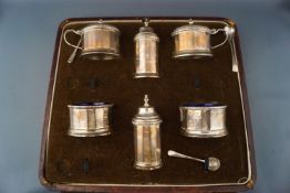 A silver six piece facetted round cruet set and three salt spoons, by with blue glass liners,