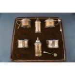 A silver six piece facetted round cruet set and three salt spoons, by with blue glass liners,