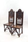 A pair of Victorian oak hall chairs with extensive carved detail,