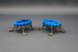 A pair of Edwardian silver oval salt cellars, each with a shaped rim on four webbed claw feet,
