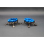 A pair of Edwardian silver oval salt cellars, each with a shaped rim on four webbed claw feet,