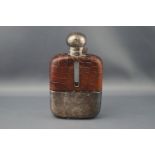 A clear glass oblong hip flask with crocodile effect brown leather mounts and a plated hinged cover