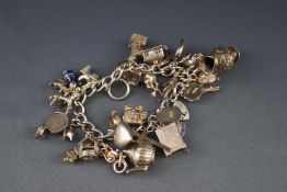 A silver charm bracelet with a padlock clasp and approximately 30 charms including a blue enamelled