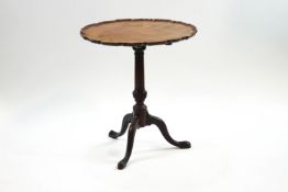 A George III mahogany tripod table, the tilt top with pie crust edge on turned column and pad feet,