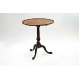 A George III mahogany tripod table, the tilt top with pie crust edge on turned column and pad feet,