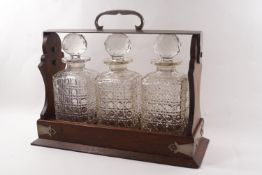 An Edwardian oak tantalus with plated mounts and three cut glass decanters and stoppers