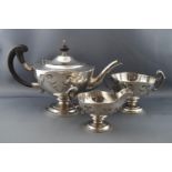 A silver round pedestal three piece tea service, each with gothic cut-card decoration,