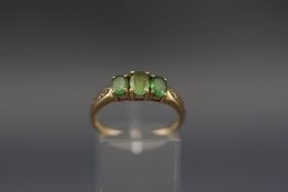 A 9ct gold and oval green-stone three-stone ring,