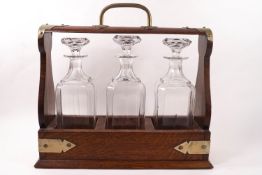 An early 20th century oak tantalus with plated mounts and three pressed glass decanters and