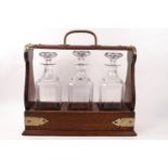 An early 20th century oak tantalus with plated mounts and three pressed glass decanters and
