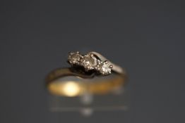 A diamond three stone cross-over ring, the early modern round brilliants approx. 0.