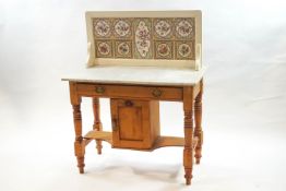 A Victorian pine washstand with marble top and tile back, single drawer above a cupboard,