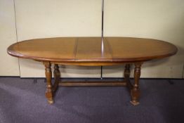 A 20th century oak extending dining table of oval shape, on turned legs with curved H-stretcher,