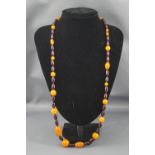An imitation red amber and orange plastic bead necklace, approx. 78cm long overall.