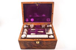 A Victorian figured walnut dressing case containing silver plated topped jars,