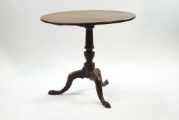 A George III style mahogany tripod table, the tilt top upon a turned column and pad feet,