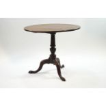 A George III style mahogany tripod table, the tilt top upon a turned column and pad feet,