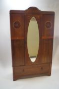 An Edwardian mahogany inlaid wardrobe, central mirrored door over one drawer below,