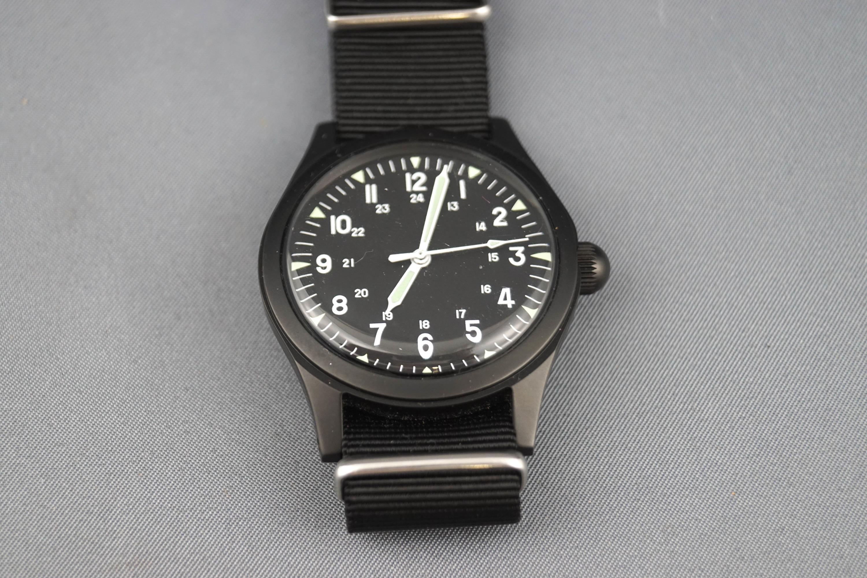 M W C, a replica US Army, Type A 1943 military wrist watch, black dial with white Arabic numerals,