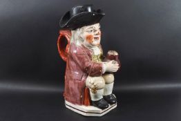 An 19th century pearlware Toby jug, modelled with a jug of ale, a pipe and tricorn hat,