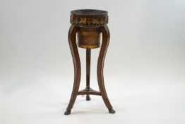 A French Empire style jardiniere stand with brass mounts of winged mythical creatures and cherubs,