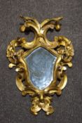 A giltwood wall mirror with shield shaped plate and scroll surround,