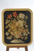 A Victorian needlepoint panel, forming a still life of flowers against a later black background,