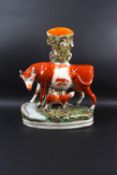 A Staffordshire pottery spill vase, modelled with a cow and calf, painted in enamels,