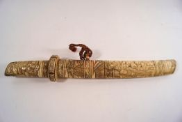 An early 20th century Japanese dagger, the ivory handle and sheath carved with figures ,